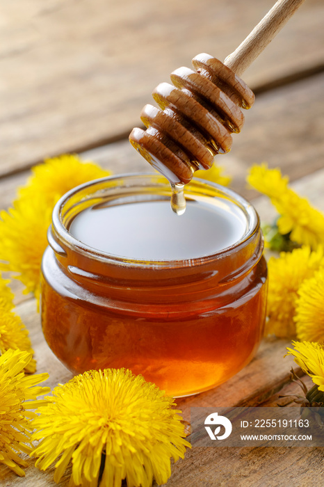 Dandelion honey in a jar on a wooden background close-up.