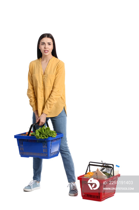 Sad young woman with shopping baskets on white background