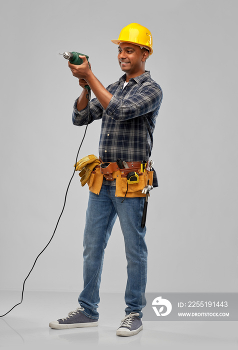 profession, construction and building - happy smiling indian worker or builder in helmet with electric drill or perforator over grey background