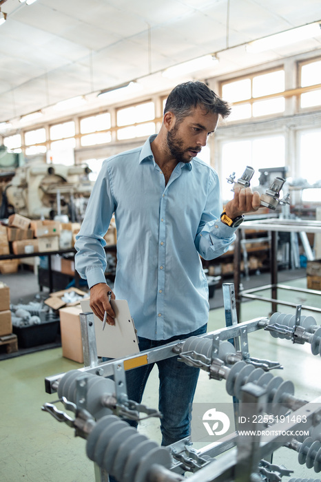 Middle age businessman doing quality control checking at industry production. Factory for industrial production of electric housings and surge arresters.