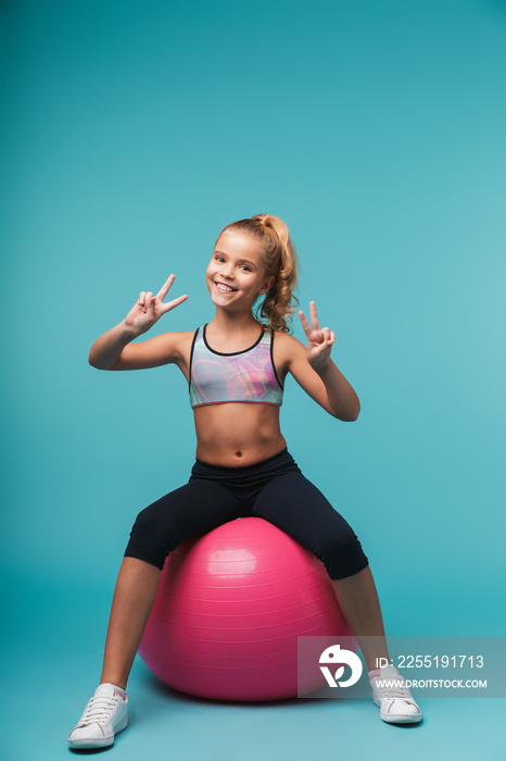 Cheerful little girl wearing sport clothes doing exercises