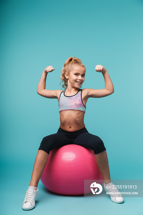 Cheerful little girl wearing sport clothes doing exercises