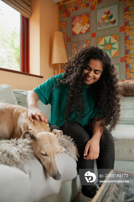 Curvy Indian girl with Cerebral Palsy petting her dog in the living room