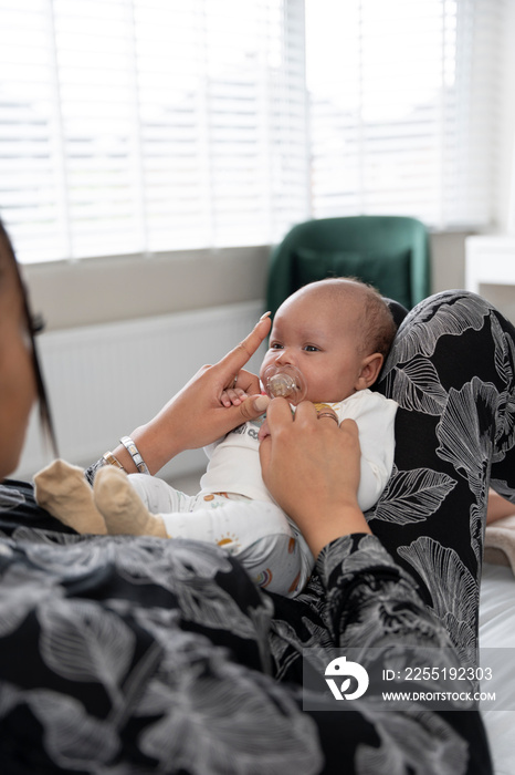 Woman giving pacifier to newborn baby girl at home