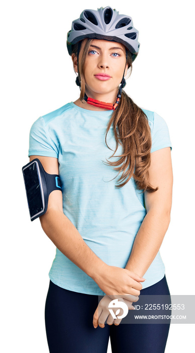 Beautiful caucasian young woman wearing bike helmet with serious expression on face. simple and natural looking at the camera.