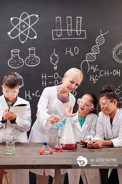 Group of clever students of secondary school watching chemical experiment