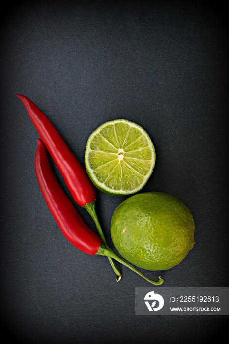 lime and red hot pepper on a black background. spice