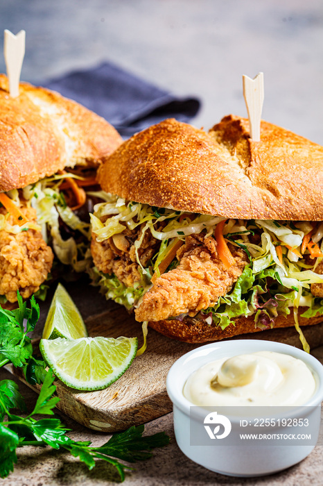 Crispy fried chicken sandwiches with coleslaw salad on the board.