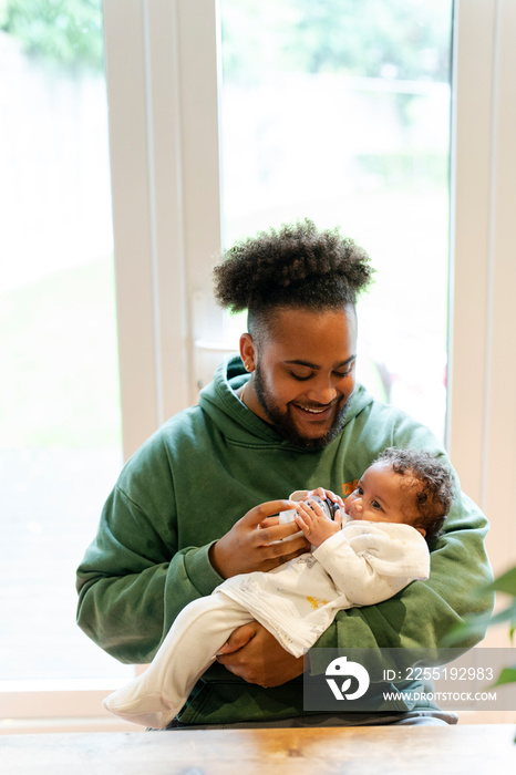 Father feeding baby daughter at home