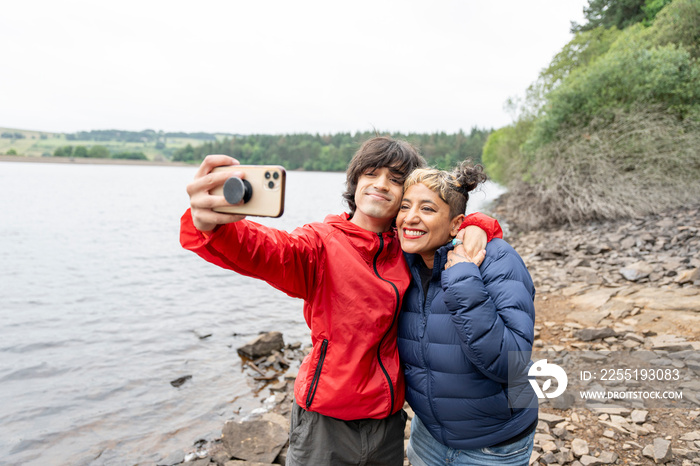 Mother and son taking selfie by lake on hike