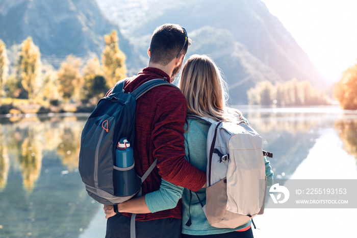 Two travel hikers in love enjoying the nature while looking the landscape in front of the lake in mountain.