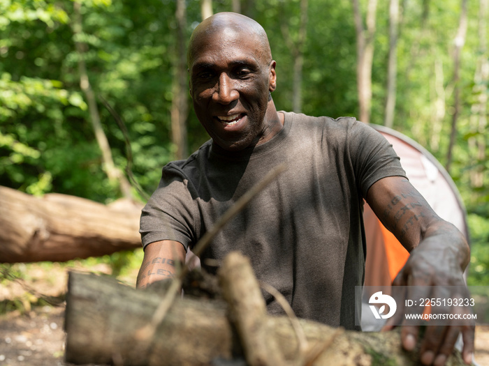 Mature man making fire in forest