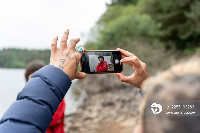 Mother photographing son by lake on hike