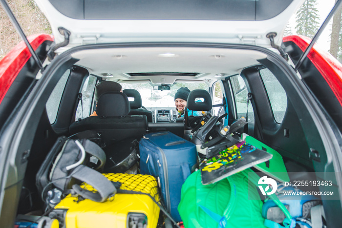 smiling woman sitting in car. snowboard in car trunk. road trip