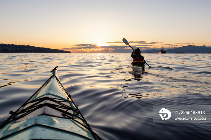 Girl Sea Kayaking during a vibrant sunny summer sunset. Taken in Vancouver, BC, Canada.