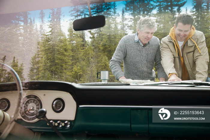 father and son reviewing map on hood of truck