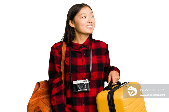 Traveler asian woman holding a suitcase isolated looks aside smiling, cheerful and pleasant.