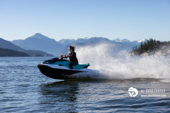 Adventurous Caucasian Woman on Sea-Doo riding in the Ocean. Lighthouse park in background. West Vancouver, British Columbia, Canada.