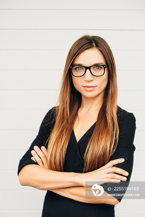 Close up portrait of beautiful young businesswoman wearing eyeglasses, arms crossed