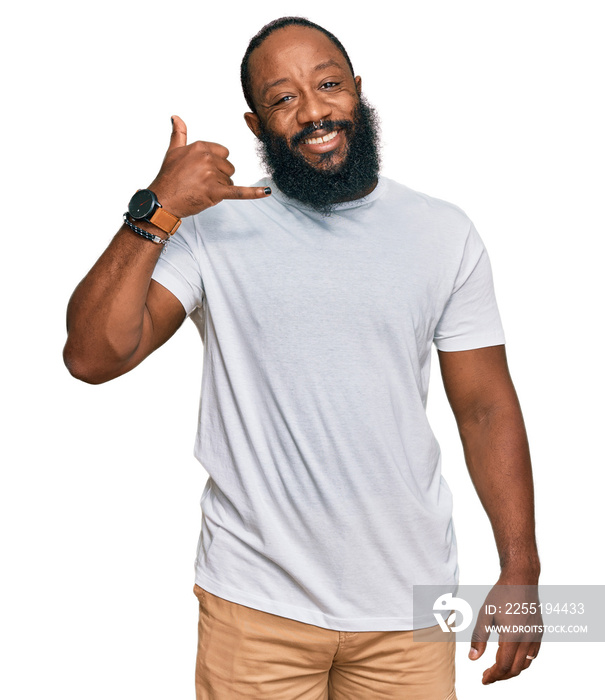 Young african american man wearing casual white tshirt smiling doing phone gesture with hand and fingers like talking on the telephone. communicating concepts.