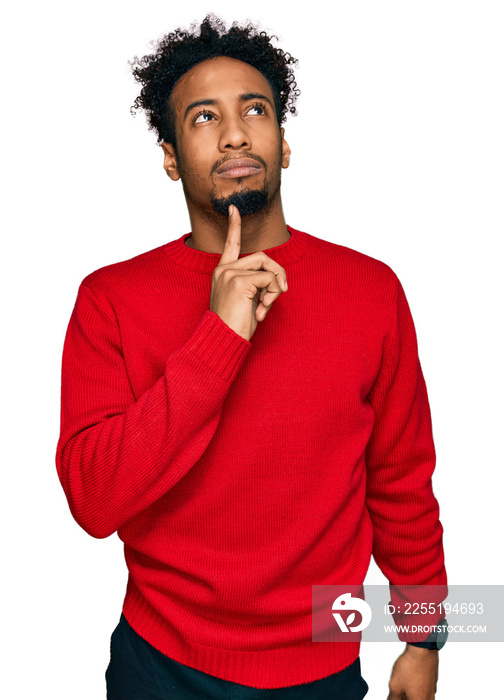 Young african american man with beard wearing casual winter sweater thinking concentrated about doubt with finger on chin and looking up wondering