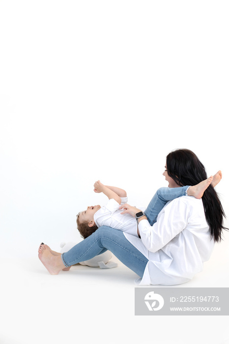 Vertical woman, boy playing on floor, white background. Hugging and tickling, caring mother, parenthood. ASD syndrome