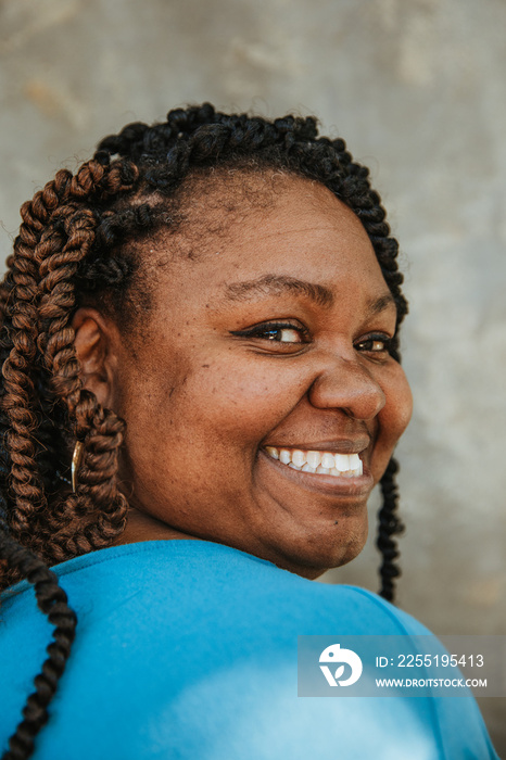 closeup portrait of a smiling plus size afro latinx haitian american woman looking over shoulder