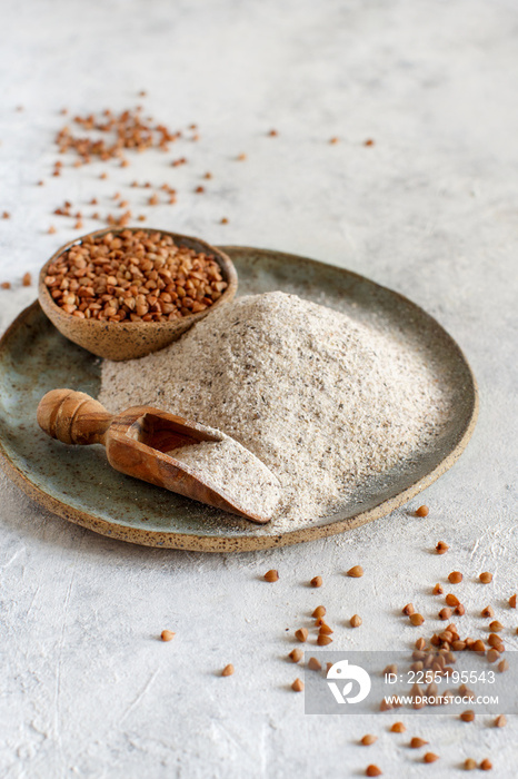 Buckwheat flour and grain with a wooden spoon on a table