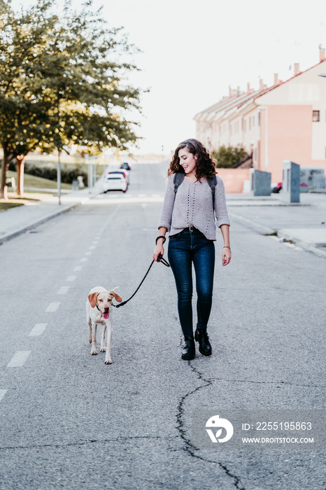 young woman and her dog outdoors walking by the street. autumn season