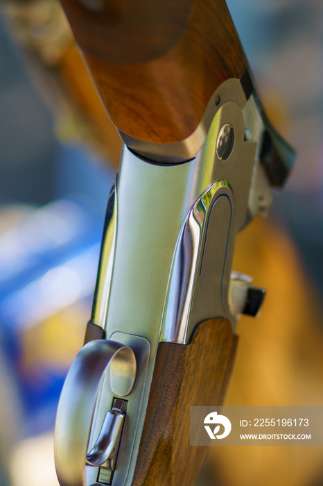 Close-up of an open, unloaded double-barreled shotgun at a sports shooting range. Blurred back.