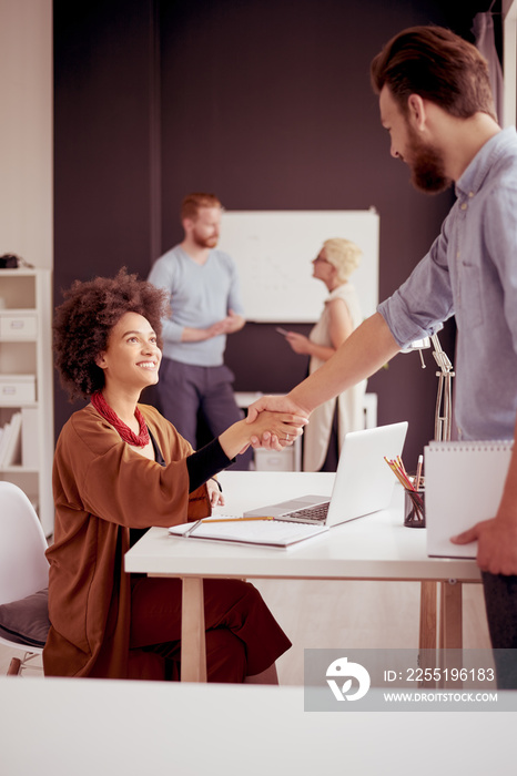 Businessman shaking hands with colleague while standing in modern office