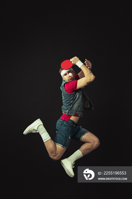 Young Caucasian funny man playing ping pong isolated on black background.