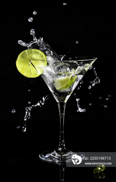 Martini splash in a cocktail glass with a slice of lime on a side