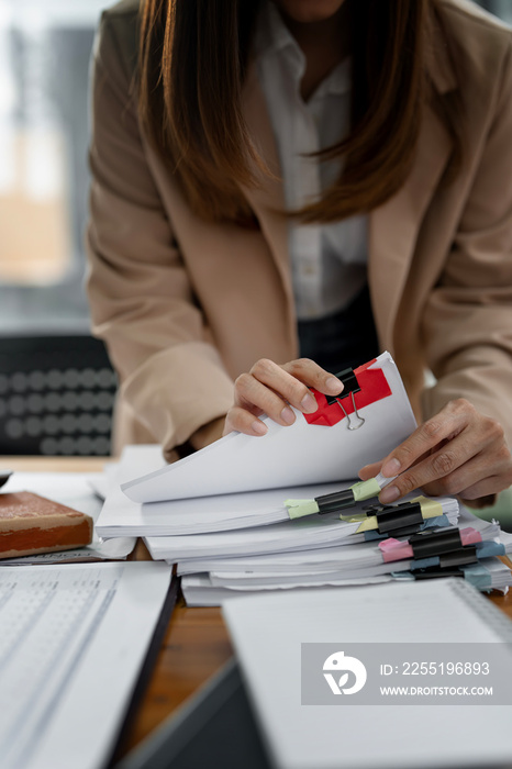 Businesswoman hands working in Stacks of paper files for searching and checking unfinished document achieves on folders papers