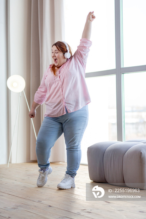 Joyful overweight woman having fun at home