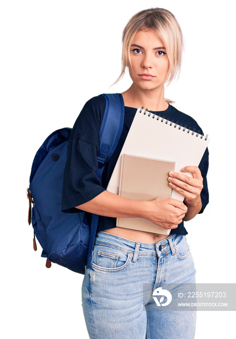 Young beautiful blonde woman wearing student backpack holding notebook thinking attitude and sober expression looking self confident