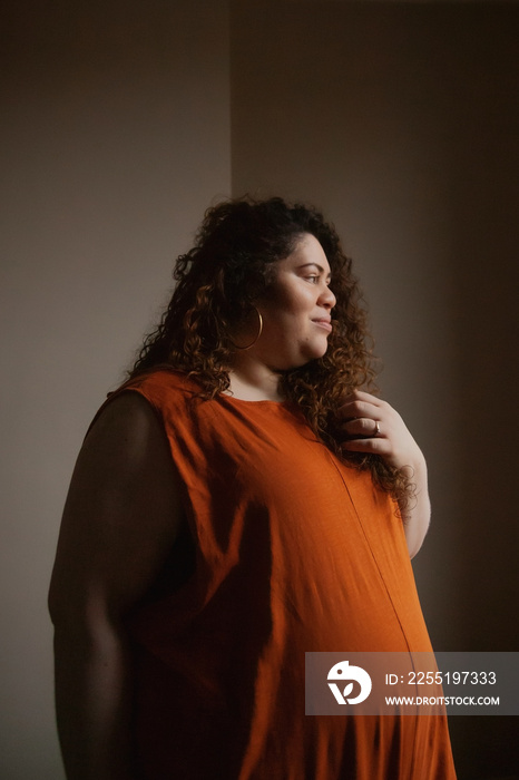 Plus-sized Sri Lankan woman with vitiligo looking out the bedroom window