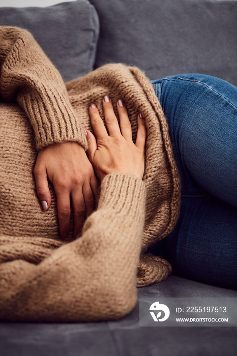 Woman having stomach issues / problems while lying on the couch.