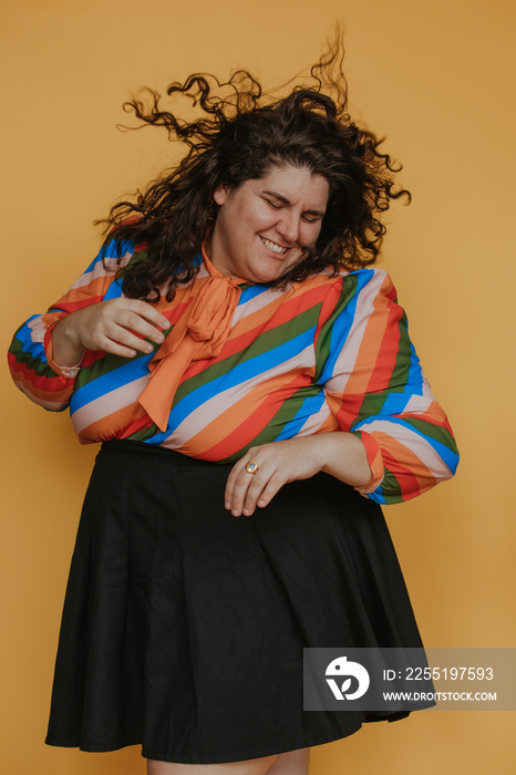 portrait of a plus size woman with a rainbow blouse dancing