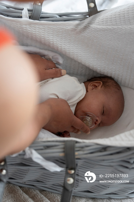 Mother putting to sleep newborn baby girl in crib