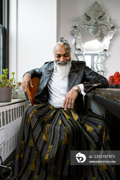 portrait of man laughing with gray hair wearing leather and skirt