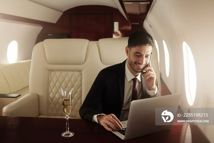 Billionaire or rich business man flying first class and working on plane with laptop and glass of champagne. Private jet concept