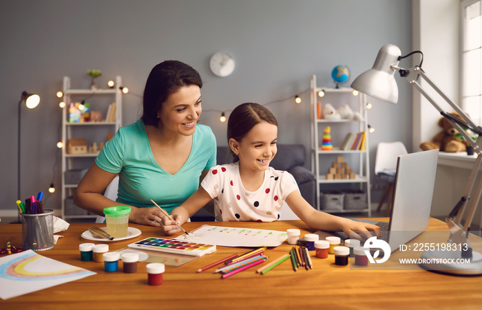 Online education of children. Mother and daughter of preschool watching a video lesson call chat creative course art drawing using lapott at home.