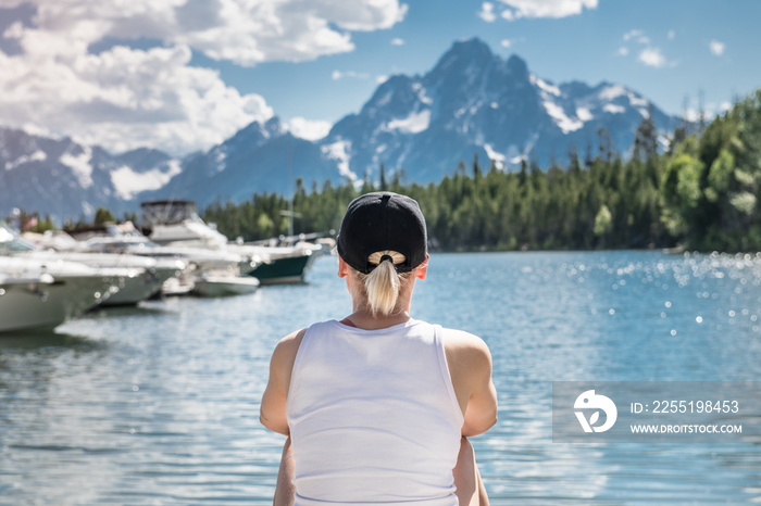 Woman travel and enjoy the nature view of a mountain lake with yachts and forest at summertime