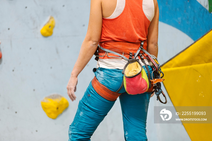 Woman getting ready for rock climb indoors.