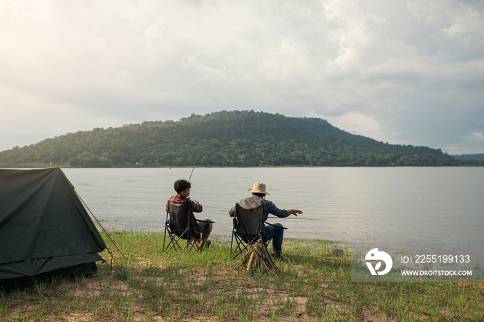 Friendship fisherman or Angler camping together and sitting a chair to fishing at the lake. Camping on the shore of the lake. Survival concept.