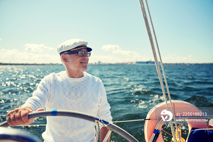 senior man at helm on boat or yacht sailing in sea