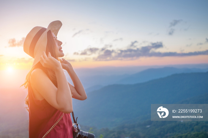 Smiling woman traveler in mountains at sunset holding hat and looking at view of nature chiangmai landmark in thailand with backpack in holiday, relaxation concept, travel concept