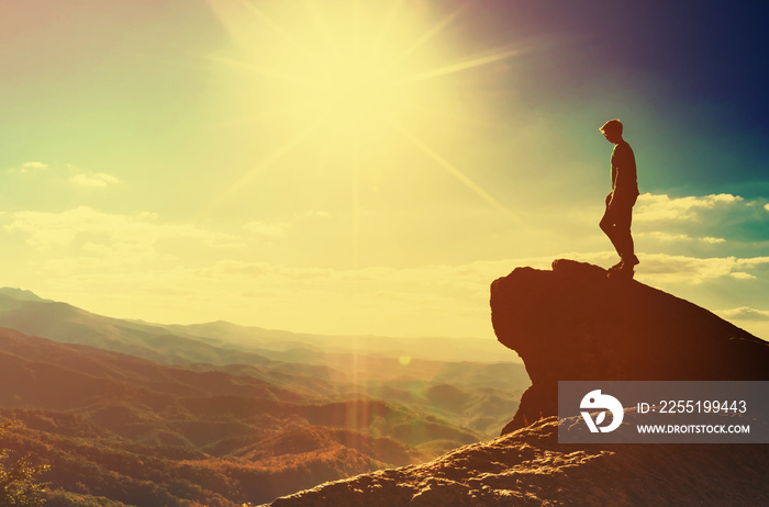 Man walking on the edge of a cliff high above the mountains