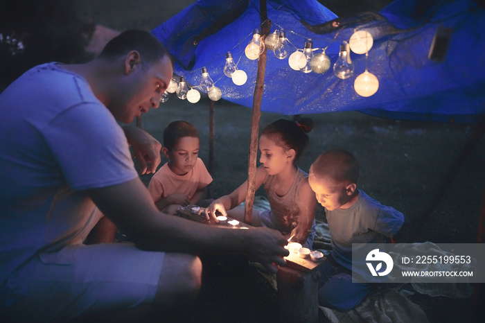 Father with children playing under their backyard tent.